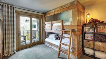 A room with a bunk bed, a ladder, a bookshelf, and a sliding glass door leading to an outdoor area.