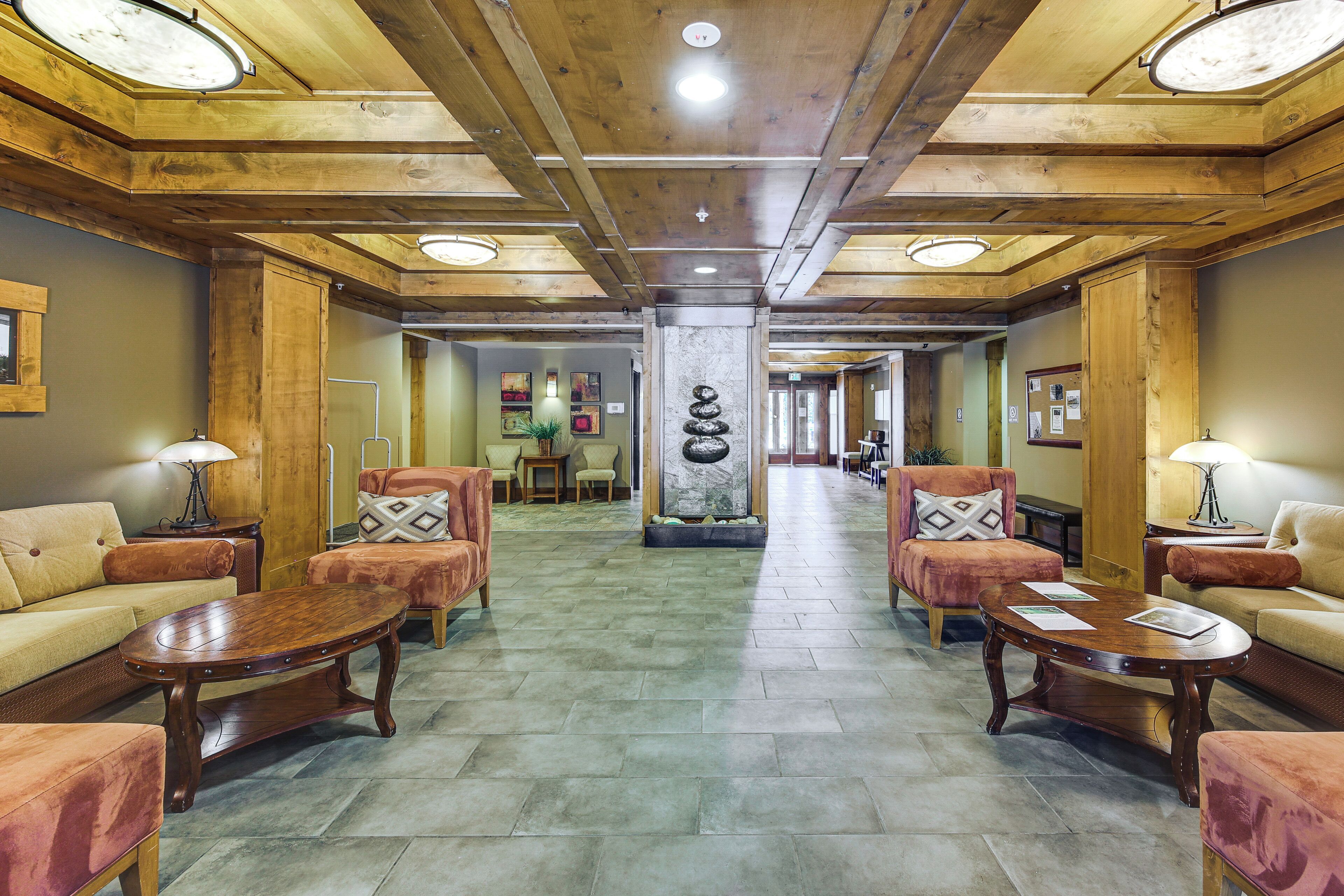 A lobby with wooden beams, a stone floor, and a central decorative wall.