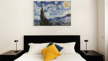 A bedroom with a bed, two nightstands, and a painting of a night sky.