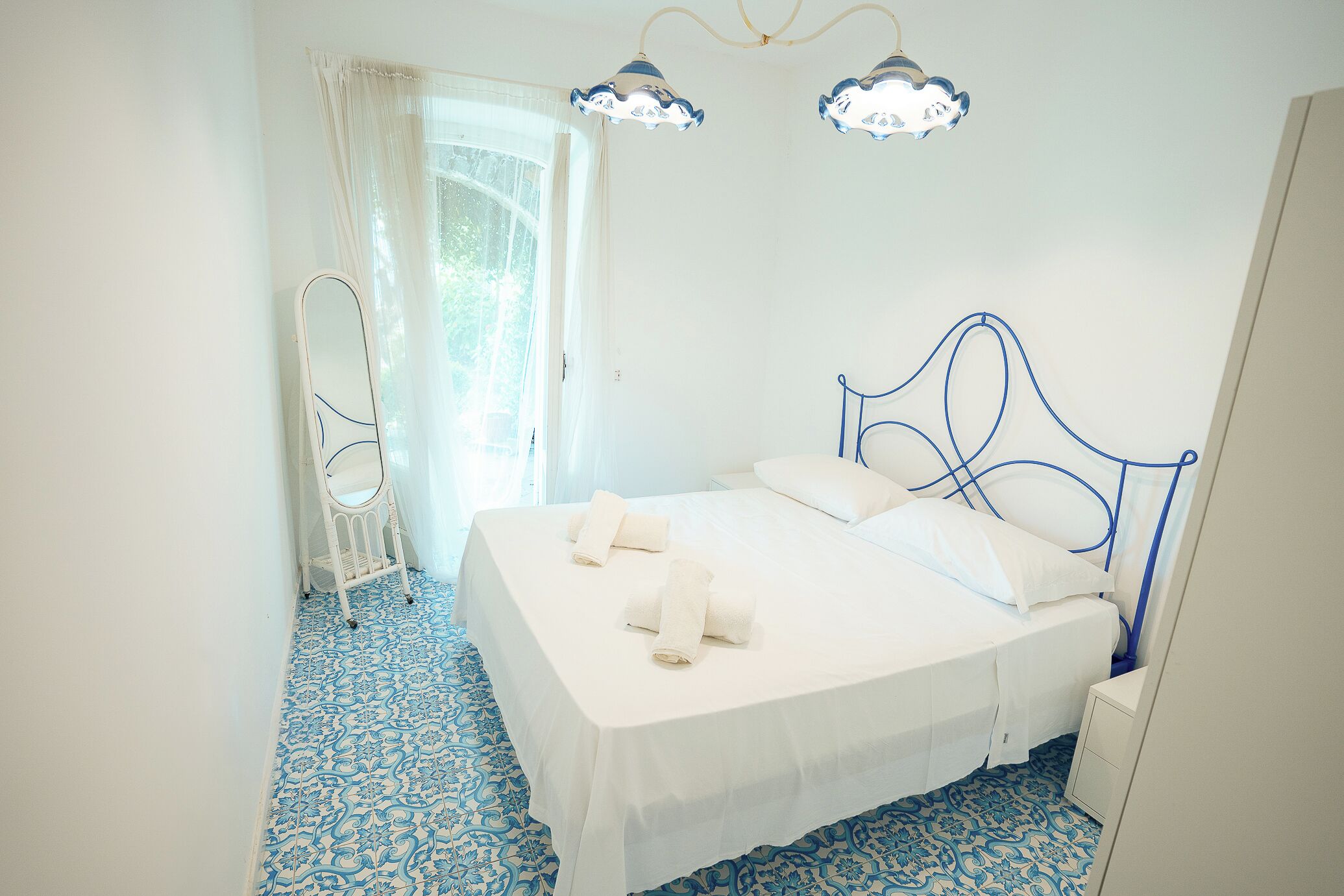 Um quarto com uma cama, um espelho e uma janela com cortinas.