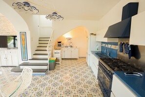 A modern kitchen with a gas stove, white cabinets, and a patterned floor. - Villa Anna (Forio)