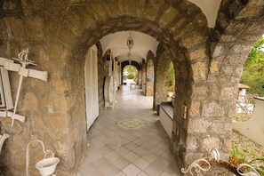 A stone corridor with arches, a tiled floor, and hanging lanterns. - Villa Anna (Forio)