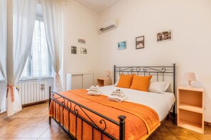 A bedroom with a bed, a radiator, a window with curtains, and a wall-mounted air conditioner. - Ostiense Stopover (Rome)