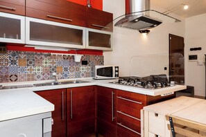 Una cucina con mobili in legno, un forno a microonde, un fornello a gas e uno schienale piastrellato.