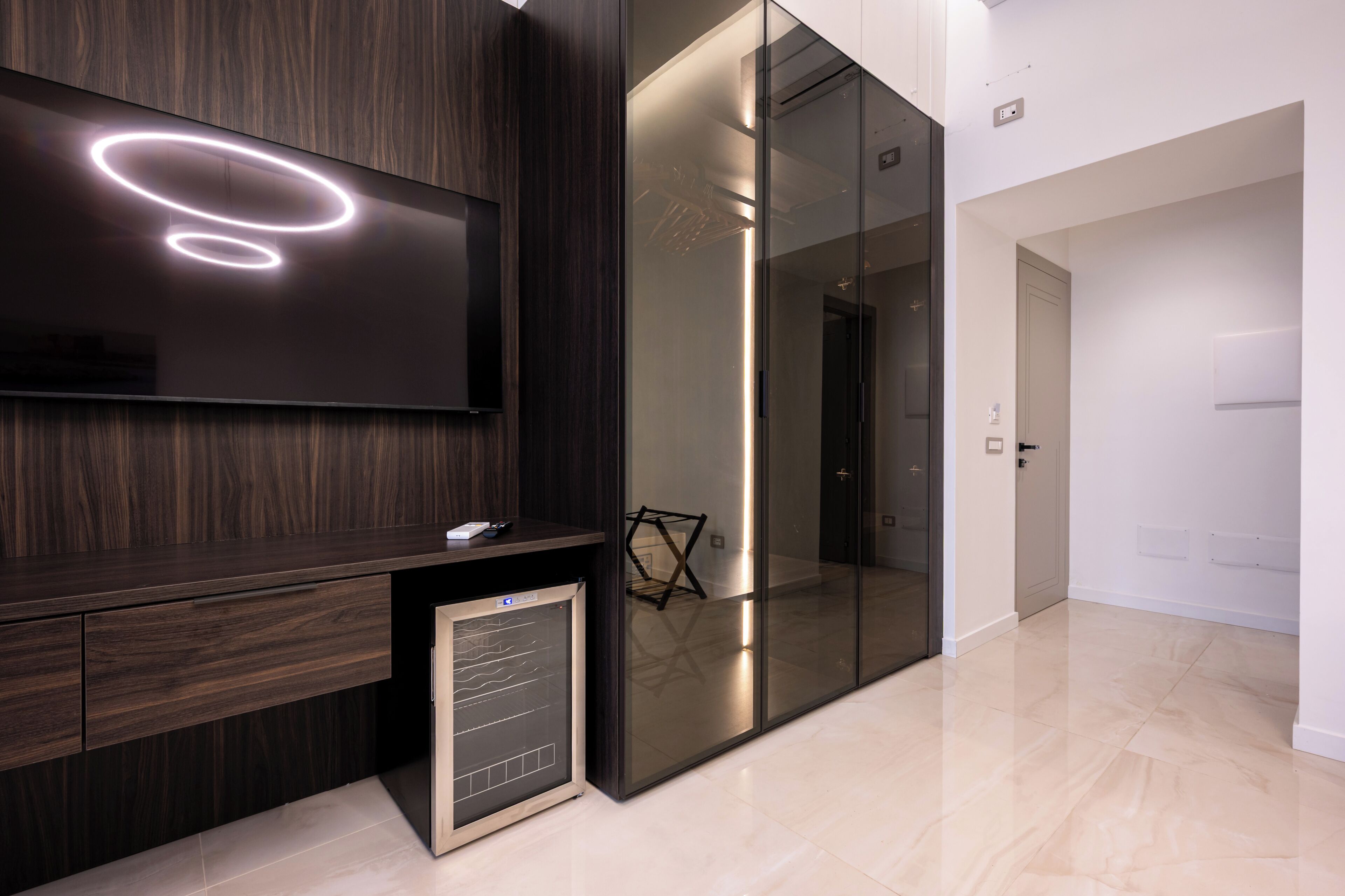 Un intérieur moderne avec un mur lambrissé en bois foncé, un téléviseur à écran plat, une cloison en verre et un design minimaliste.