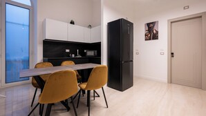 Una cocina moderna con una mesa de comedor, sillas y un refrigerador negro.