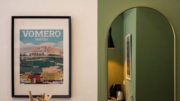 A framed cityscape poster, a mirror, and a small table with a coffee machine.