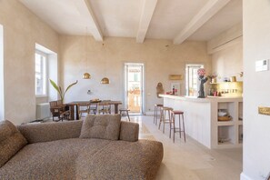 A spacious living area with a sofa, dining table, and kitchen area with stools. - Labicasa (Rome)