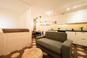 A compact living space with a sofa, a dining area, and a kitchenette. - Vico Santa Luciella 20 (Naples)