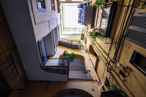 A narrow, multi-level courtyard with balconies, railings, and potted plants. - Vico Santa Luciella 20 (Naples)
