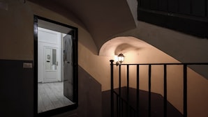 Un escalier avec une rampe noire et une applique murale éclairée.