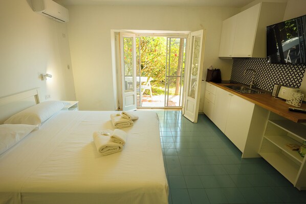 A hotel room with a bed, a bathroom, a kitchen, and a view of the outdoors. - Villa La Pigrizia (Forio)