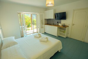 Ein Schlafzimmer mit einem Bett, einem Fernseher und einer Küchenzeile.