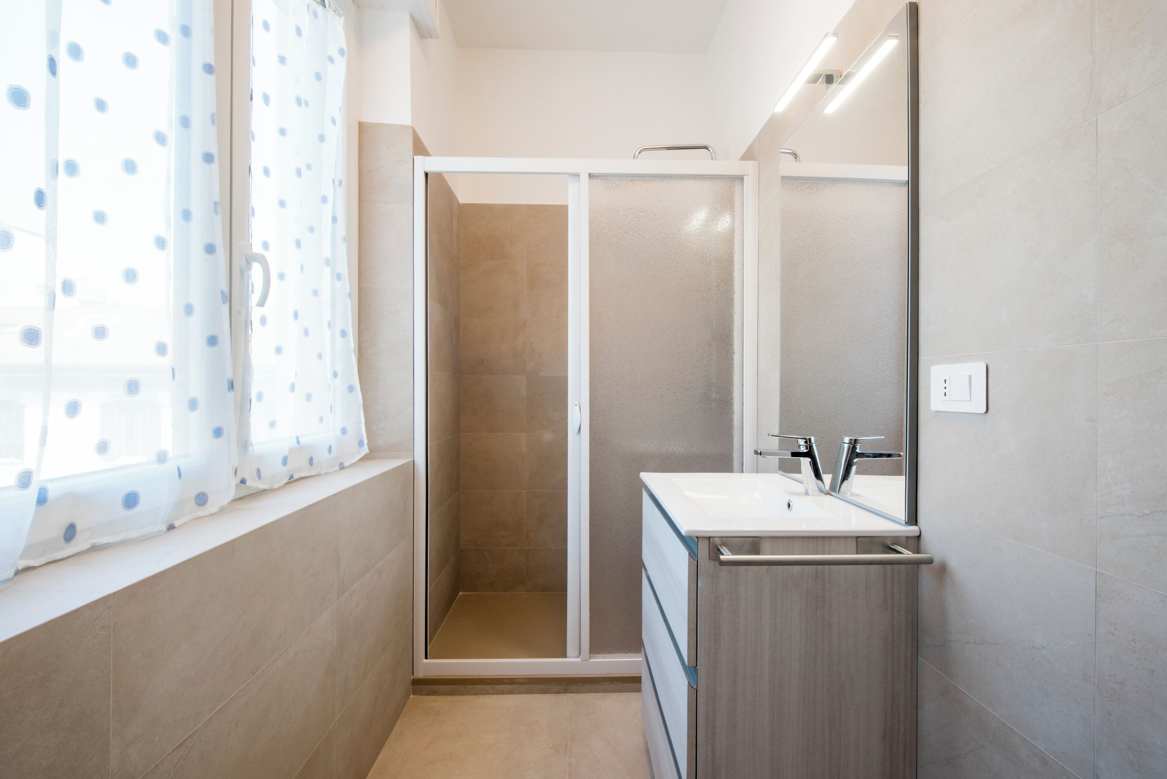 Ein Badezimmer mit Dusche, Waschbecken und Spiegel.