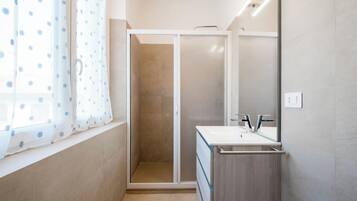 Ein Badezimmer mit Dusche, Waschbecken und Spiegel.