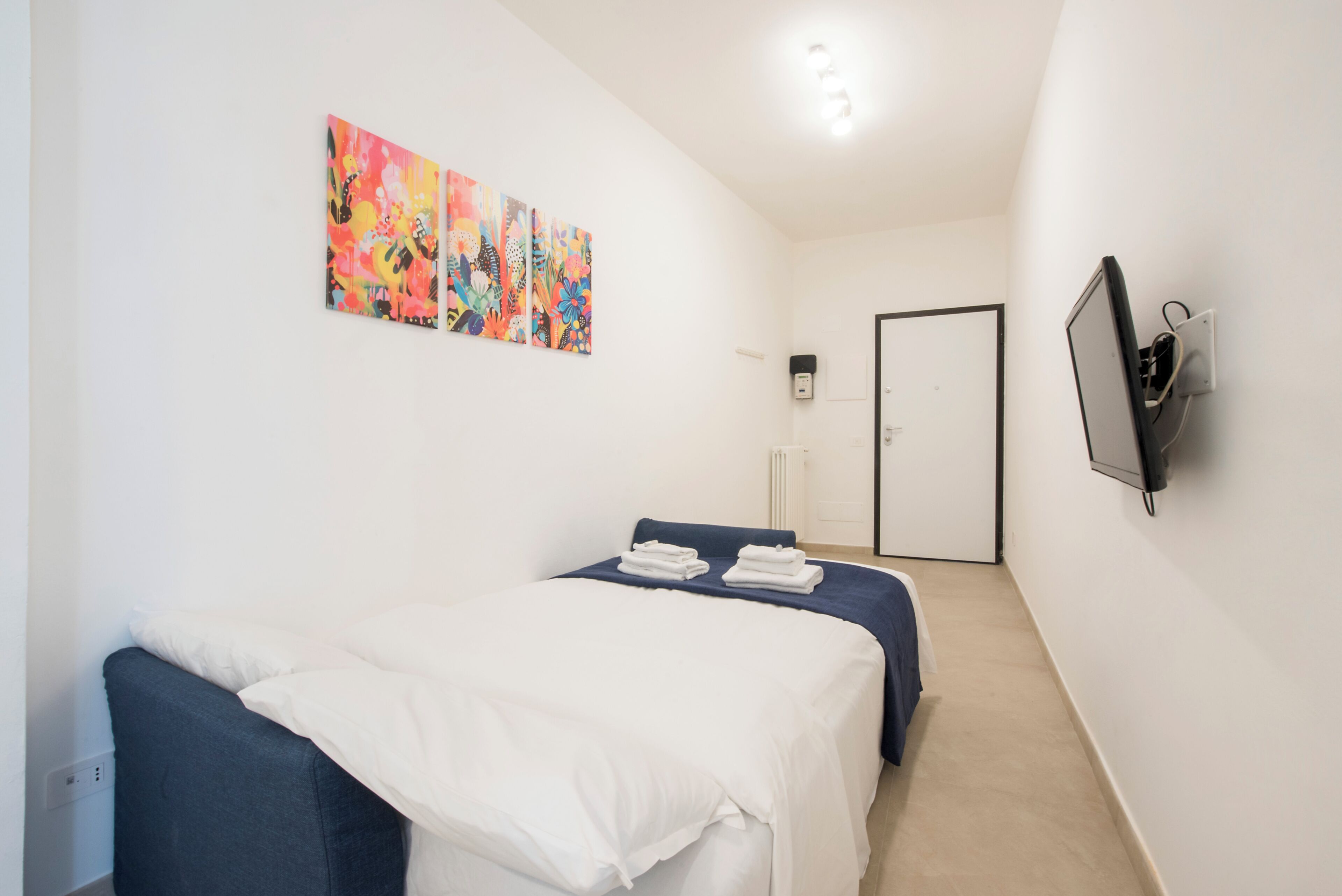 Un dormitorio con dos camas, un televisor y arte abstracto en la pared.