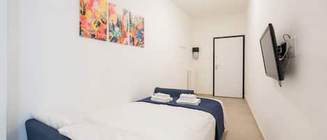 Un dormitorio con dos camas, un televisor y arte abstracto en la pared.