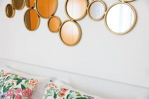 Ein Bett mit Kissen mit Blumenmuster und eine Wand mit mehreren runden Spiegeln.