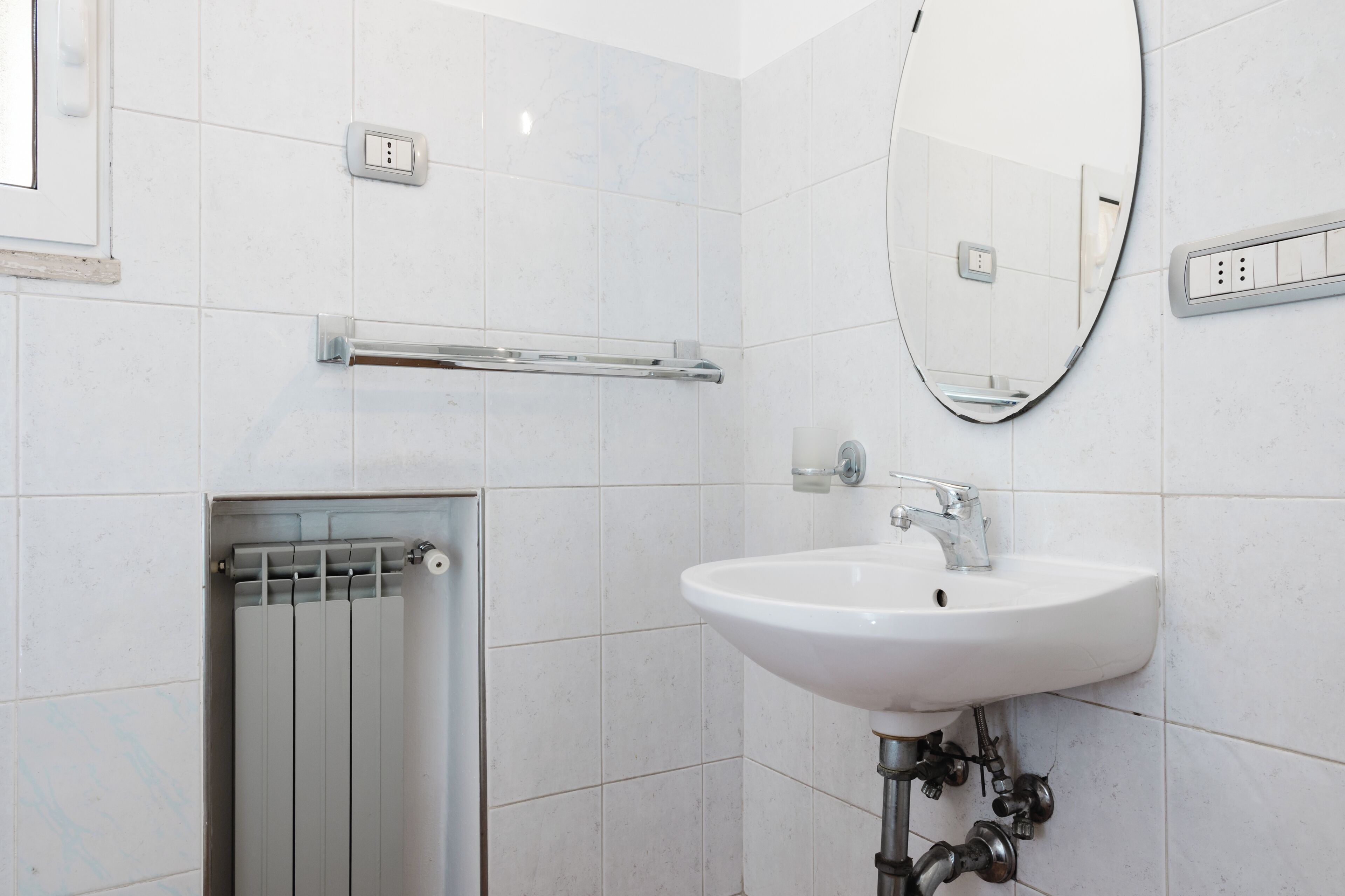 A modern bathroom with a white sink, a mirror, and a towel rack.