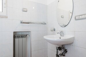 Un baño moderno con un lavamanos blanco, un espejo y un perchero para toallas.