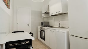 Eine kleine Küche mit weißen Schränken, einer Mikrowelle, einem Backofen und einem Spülbecken.