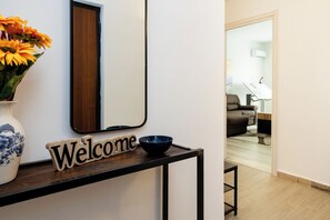 A reception desk with a 'Welcome' sign, a vase with flowers, and a mirror. - Vatican Giulianos House (Rome)
