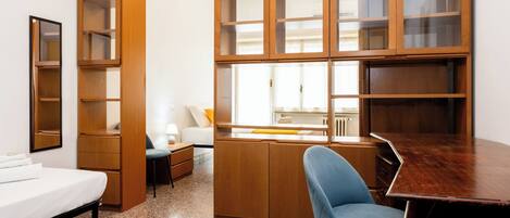 Une pièce de taille modeste comprenant un lit, un bureau, une chaise et des étagères en bois intégrées.
