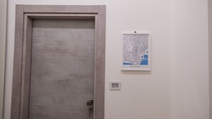 Een gesloten deur met een eenvoudig handvat, een lichtschakelaar op de muur en een inlijsting kaart.