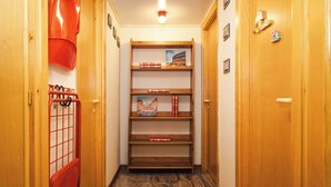 Ein Flur mit Holztüren, einem roten Sessel und einem Bücherregal mit Büchern und einem gerahmten Bild.