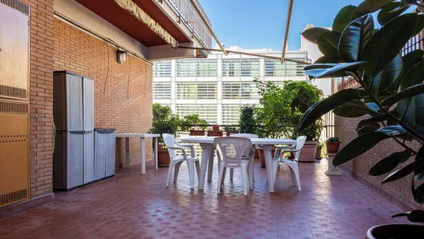 Eine Terrasse mit Tisch und Stühlen, Topfpflanzen und einer Ziegelwand.
