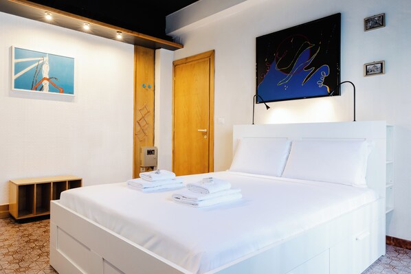Een hotelkamer met een opgemaakt bed, een houten deur, een aan de muur bevestigde televisie en een klein plankje.