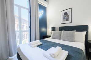 Una habitación de hotel con una cama grande, ropa de cama blanca, un cabecero oscuro y un cuadro en la pared.
