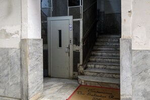 Un escalier de marbre mène à une porte sur laquelle est apposée une enseigne indiquant « Poumon ».
