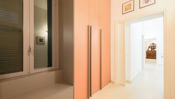 A hallway with a sliding door, a set of cabinets, and a clock on the wall.