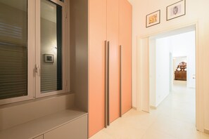 Un couloir avec une porte coulissante, un ensemble de placards et une horloge au mur.