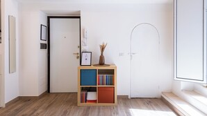 A hallway with a wooden floor, a white door, a bookshelf with books and a vase, and a framed certificate on the wall. - Archetto by the Vatican (Rome)