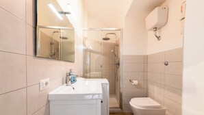 A modern bathroom with a glass-enclosed shower, a white sink, and a toilet. - Archetto by the Vatican (Rome)