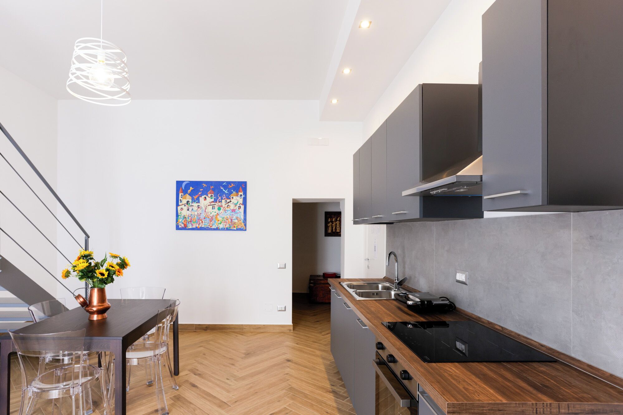 Une cuisine moderne dotée d’un plan de travail en bois, d’appareils électroménagers en acier inoxydable et d’un parquet en chevrons.