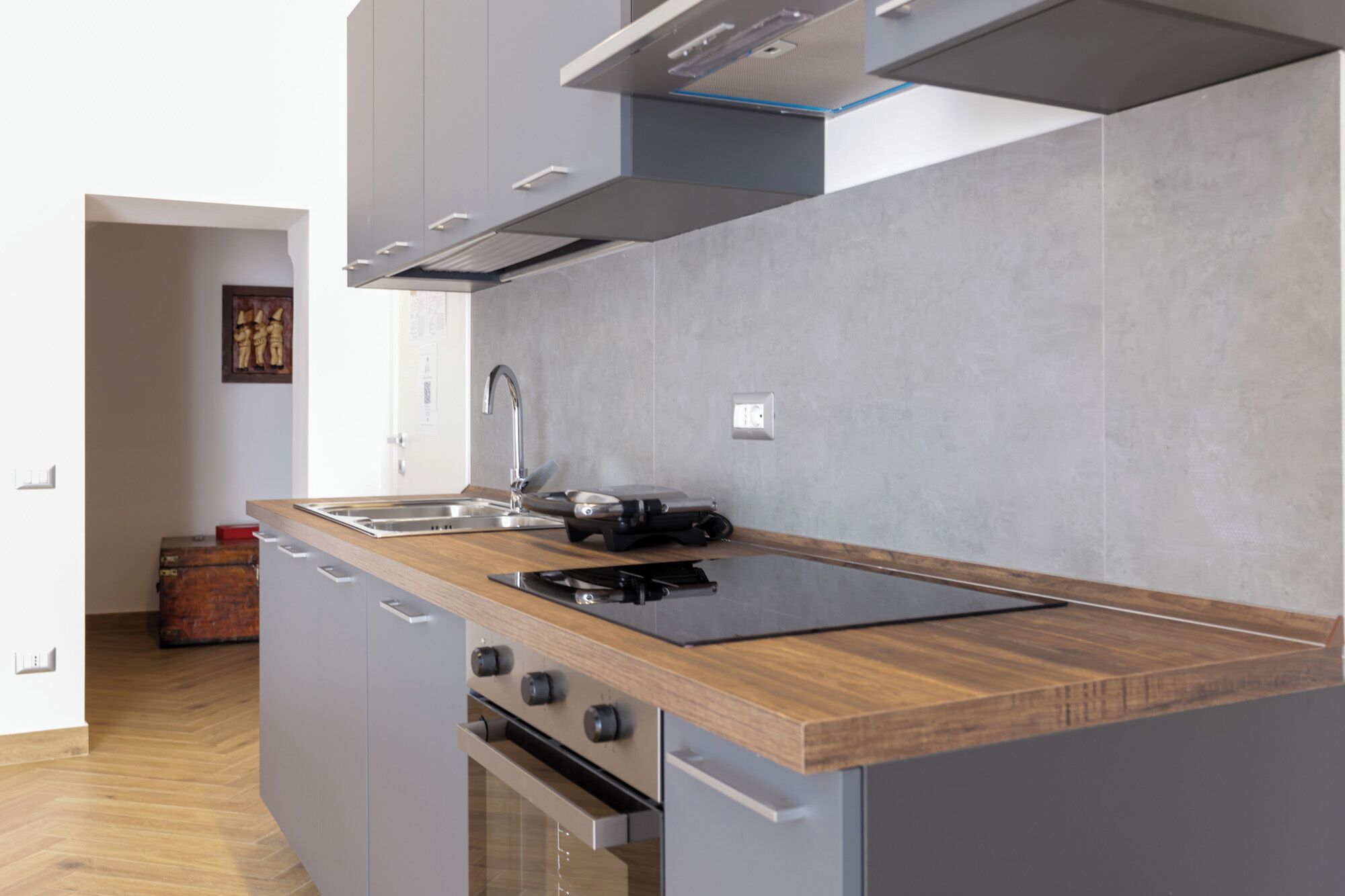 Una cocina moderna con encimera de madera, pileta de acero inoxidable y horno empotrado.