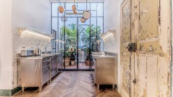 Una cocina moderna con electrodomésticos de acero inoxidable, suelo de madera en espiga y vistas a un jardín a través de puertas de vidrio.