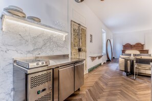 A modern kitchen with a marble countertop, stainless steel appliances, and a herringbone wooden floor. - EVA Loft (Rome)