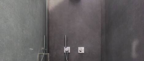 A modern shower area with a glass door, a handheld showerhead, and a wall-mounted control panel.