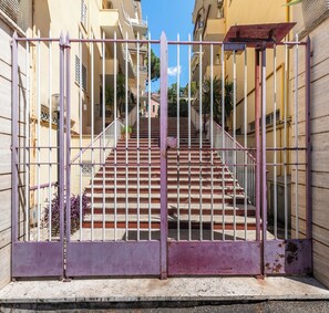 Ein verschlossenes Eingangstor mit einer Treppe, die zu einem Gebäude mit Balkonen führt.