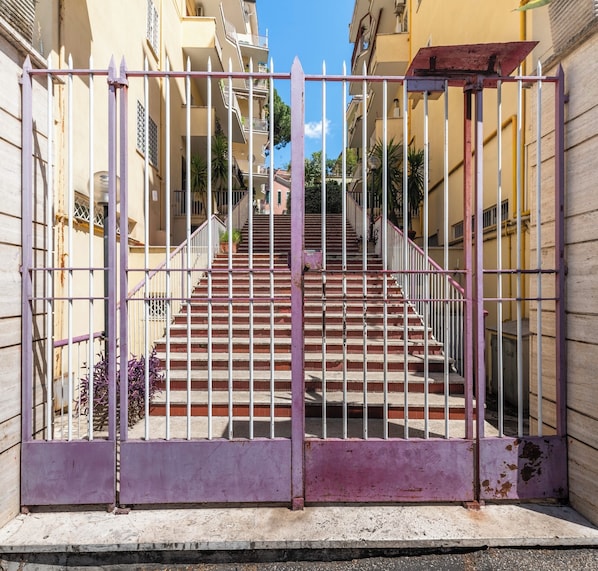 A gated entrance with a staircase leading to a building with balconies.
