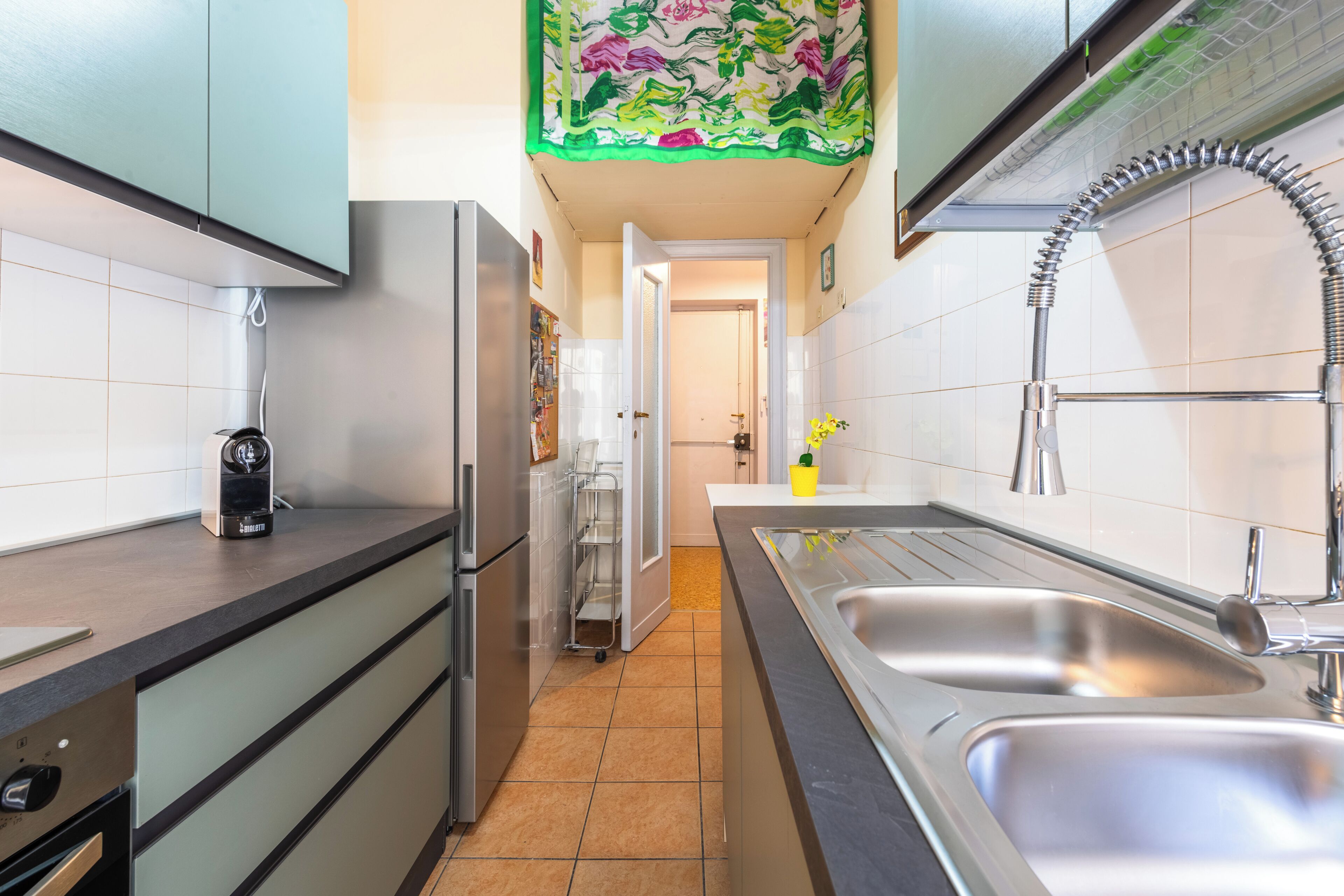 A modern kitchen with stainless steel appliances, a double sink, and a tiled backsplash.