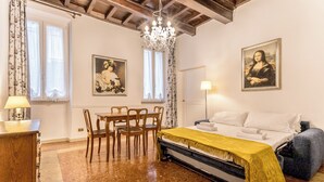 A bedroom with a bed, a desk, chairs, a chandelier, and two paintings on the wall. - Casa Iside (Rome)