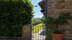A brick building with a metal gate leading to a paved area. - Olivetello  (Trevignano Romano)