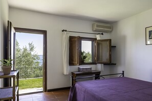 A bedroom with a bed, a window with curtains, a potted plant, and a view of greenery. - Olivetello  (Trevignano Romano)