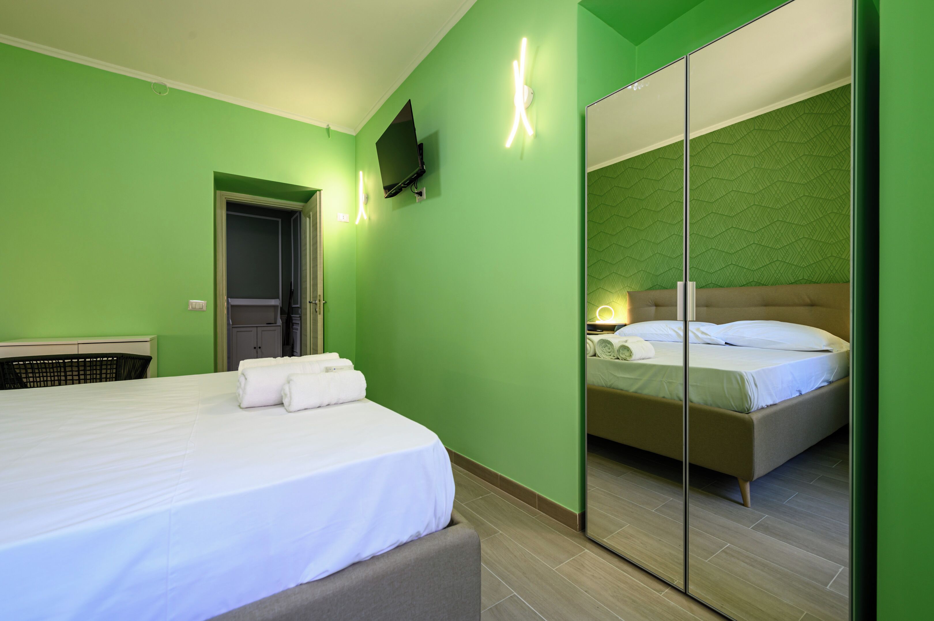 Ein Hotelzimmer mit Bett, Wandfernseher und Spiegelkorpus.