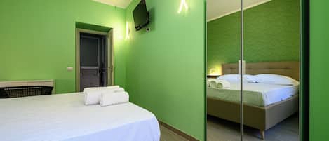 Una habitación de hotel con una cama, un televisor montado en la pared y un armario con espejo.